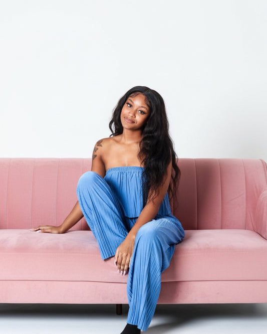 Woman sitting on a pink couch in a professional studio for a clothing boutique photoshoot.