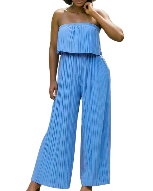 Woman wearing a blue pleated jumpsuit standing outdoors.