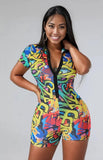 Woman wearing a colorful 90s theme romper with buttons against a plain background