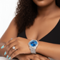 Woman wearing a silver watch with a blue face on a white background