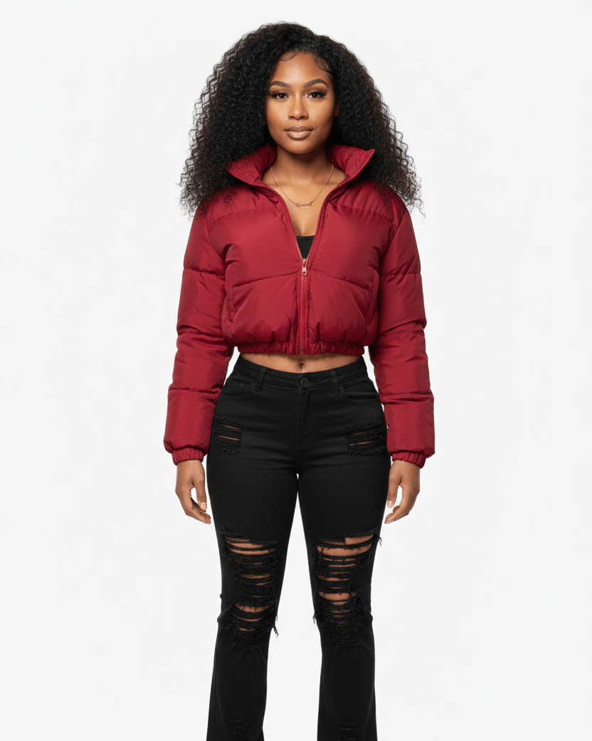 Woman wearing a burgundy puffer jacket and black ripped jeans on a white background