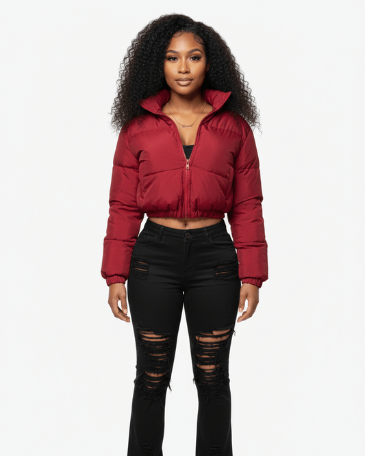 Woman wearing a burgundy puffer jacket and black ripped jeans on a white background