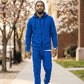 Man wearing a blue tracksuit walking on a sidewalk with cherry blossom trees in the background