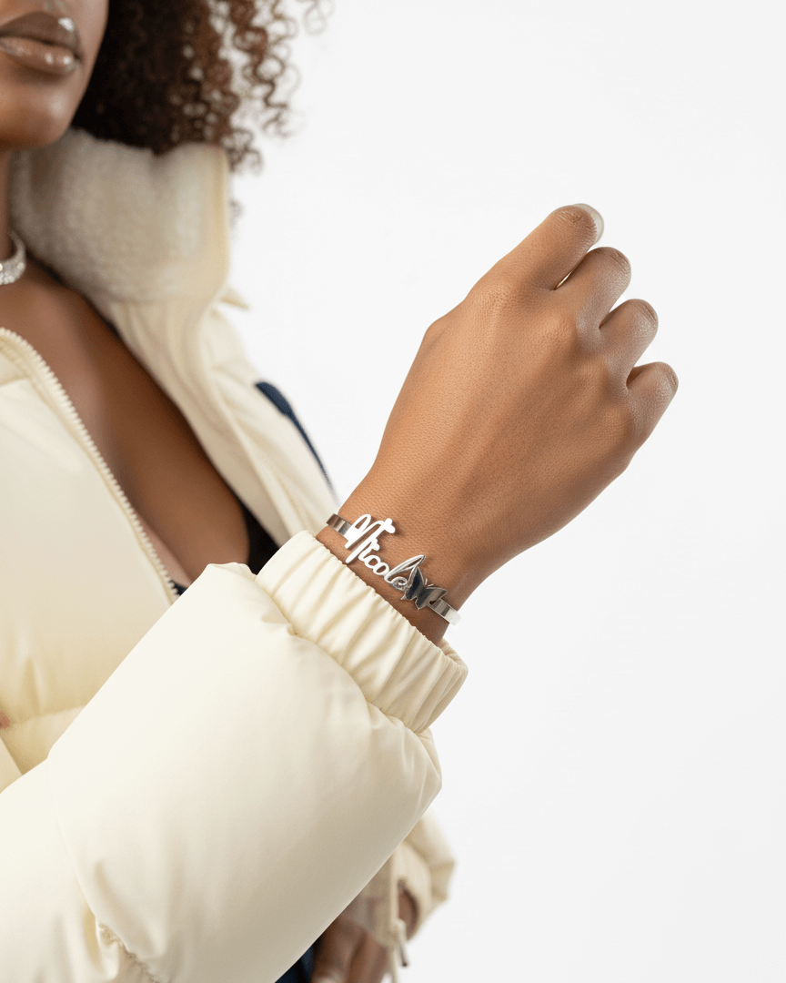 Person wearing a bracelet withher name on it against a neutral background