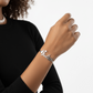 Person wearing a silver bracelet with 'Nicole' on a plain background