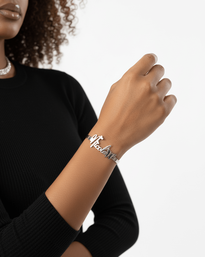 Person wearing a silver bracelet with 'Nicole' on a plain background