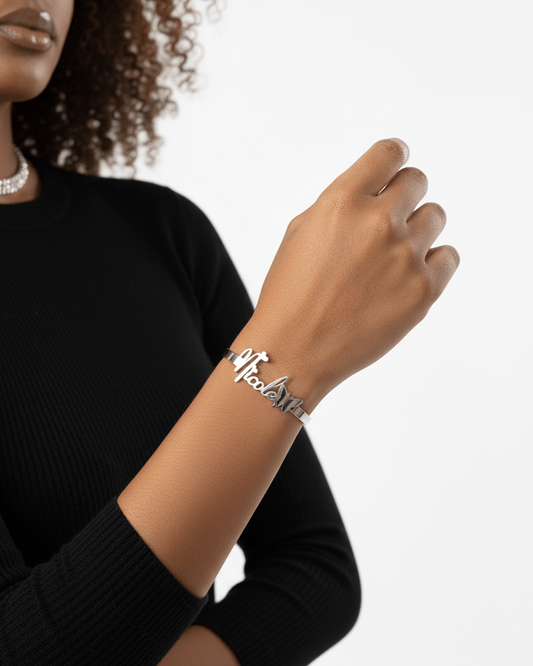 Person wearing a silver bracelet with 'Nicole' on a plain background