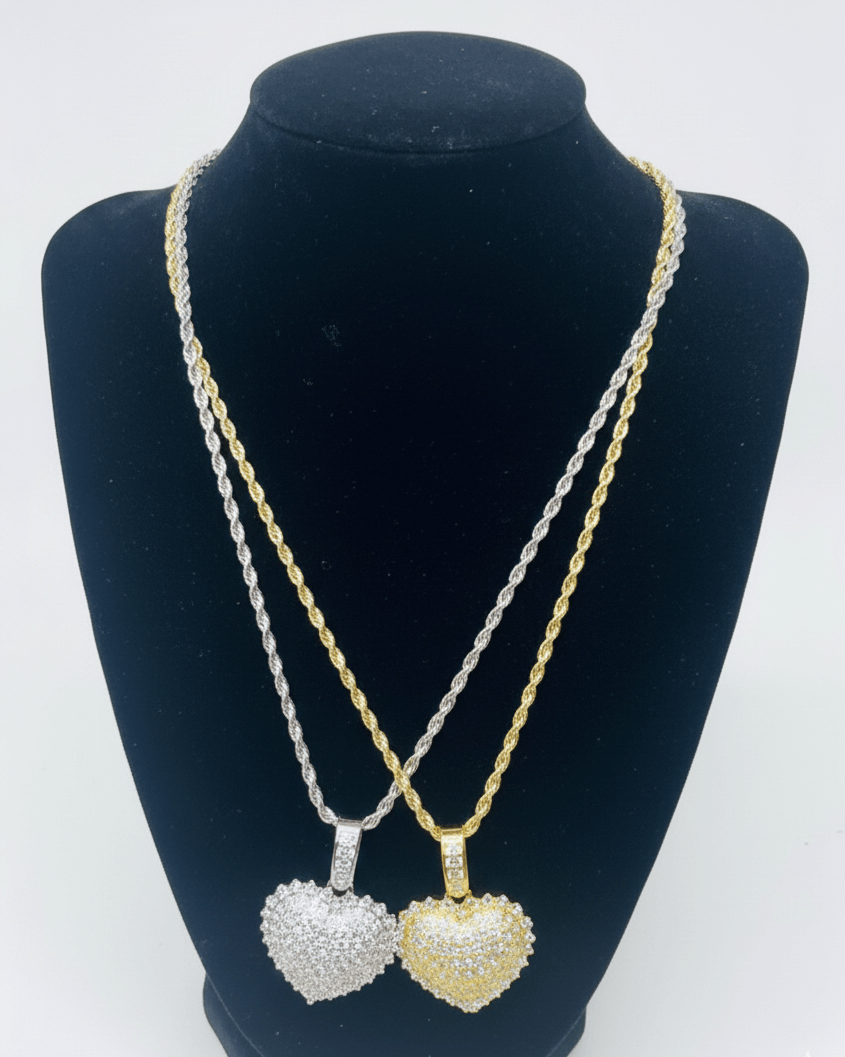 Two heart-shaped pendants on gold and silver necklaces displayed on a black mannequin bust.