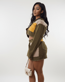 Woman wearing a green and yellow jacket matching skirt set with a white background