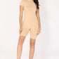 Woman wearing a nude beige bodysuit romper with a zipper on a white background
