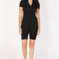 Woman wearing a black zip-up romper with white sneakers on a white background