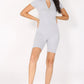 Woman wearing a gray knit romper and white tennis shoes on a white background