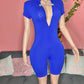 Mannequin wearing a blue romper  jumpsuit with a deep v neckline against a pink wall.