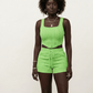 Person wearing a bright green outfit with white sneakers on a plain background