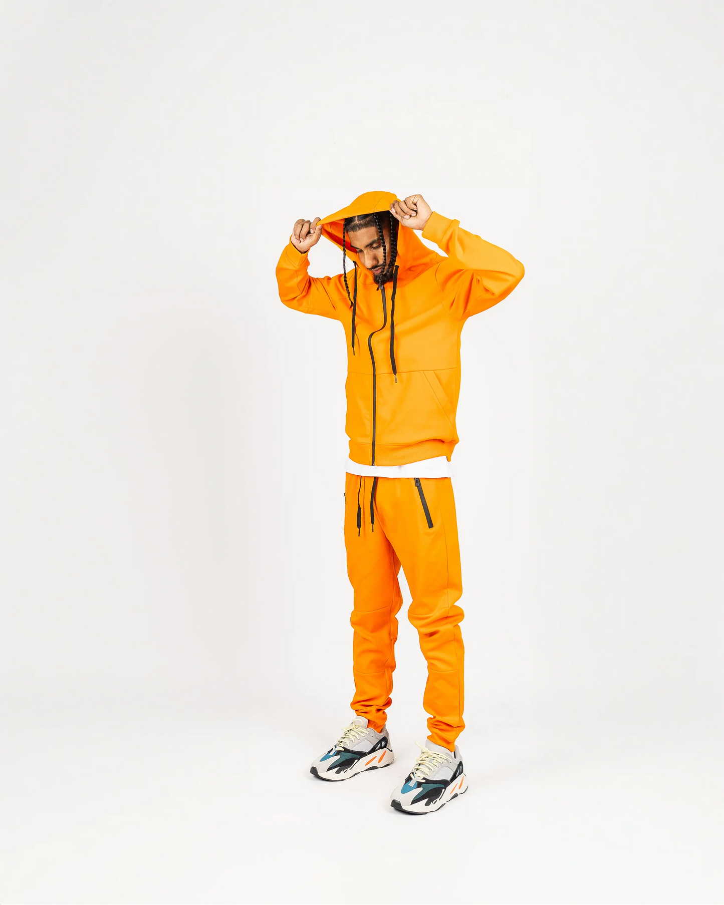 Orange men’s tech fleece matching set worn post-workout at gym, Yeezy Wave Runners visible, relaxed confident look.