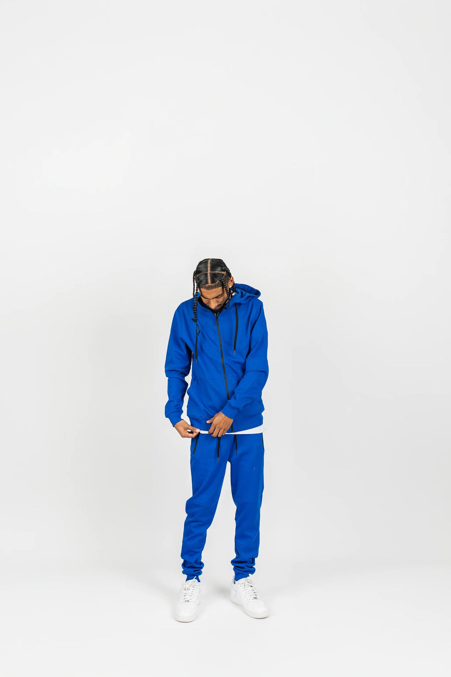Side-angle view of royal blue men’s matching sweatsuit with hands in pockets, white background.