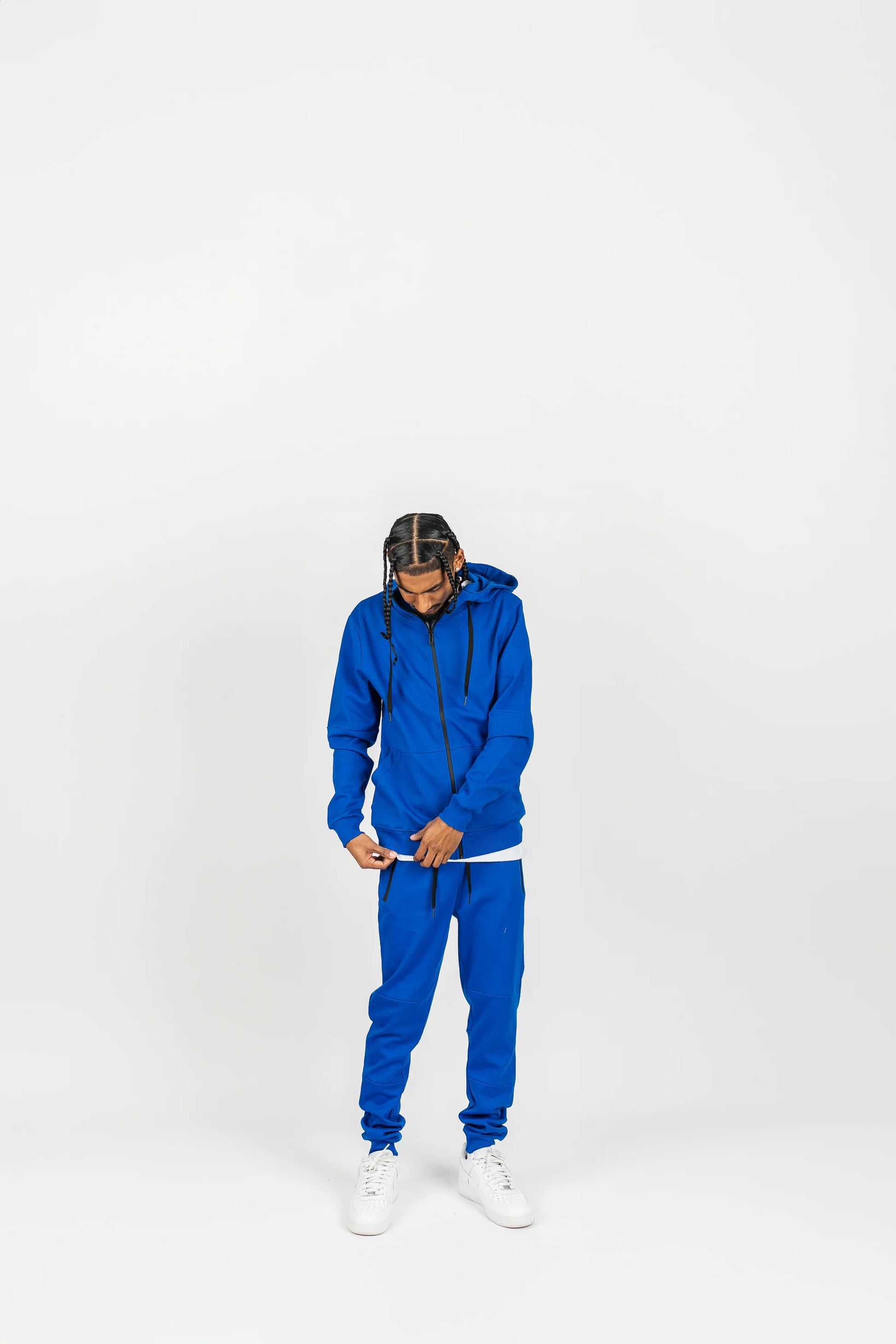 Side-angle view of royal blue men’s matching sweatsuit with hands in pockets, white background.