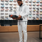 Foot Action newest jordan releases for men. Lifestyle photo of man in white tech fleece tracksuit styled with Jordans at the mall.
