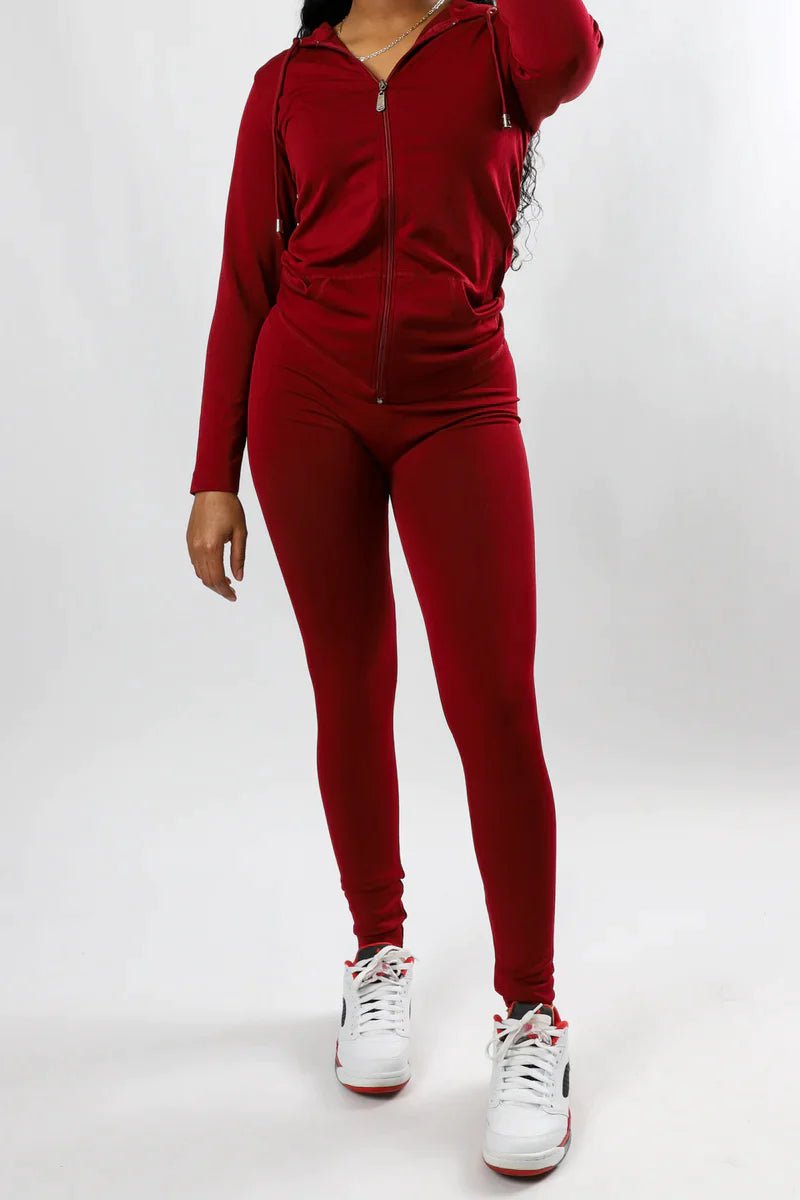 Model in burgundy two-piece tracksuit and burgundy and white Jordans on white studio backdrop