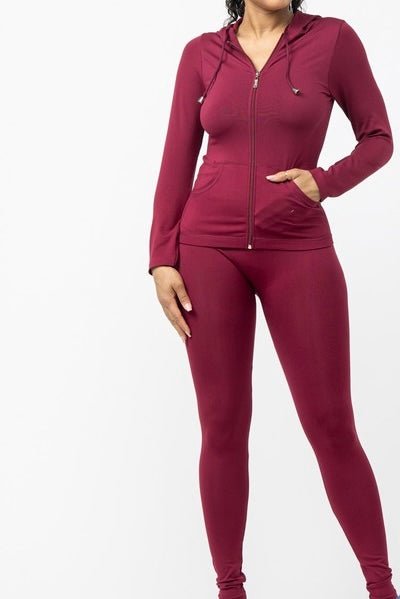 Plus-size model in burgundy two-piece leggings set styled with sneakers and bag for casual fall outfit