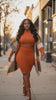 black women in orange outfit with sweater cardigan and brown fall boots  with long bouncy curly hair
