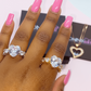 Hand wearing two diamond rings with pink nail polish on a blurred background