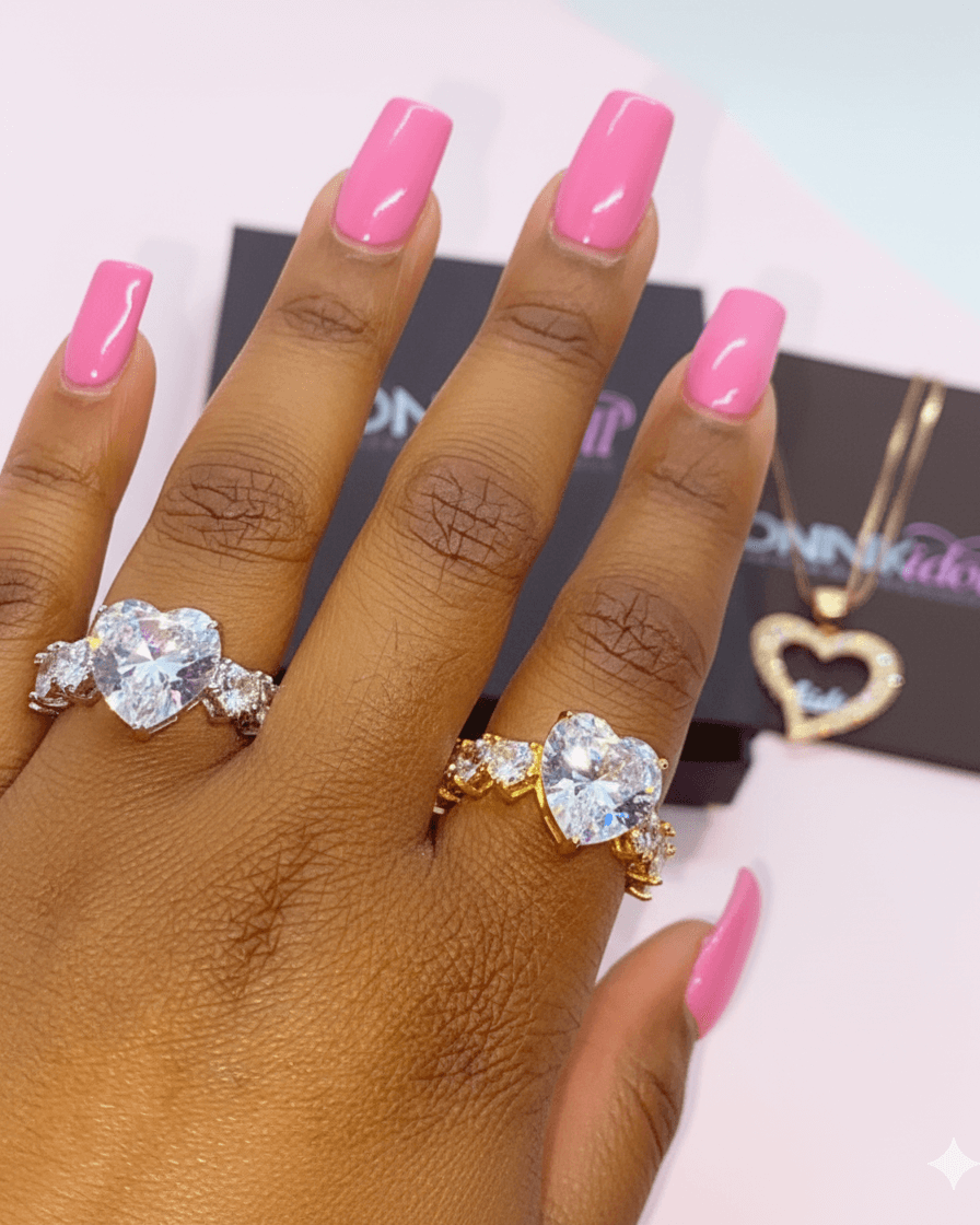 Hand wearing two diamond rings with pink nail polish on a blurred background