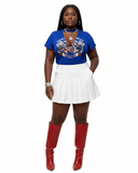 Person wearing a blue graphic t-shirt, white pleated skirt, and red boots on a white background