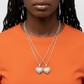 Person wearing two heart-shaped pendants on a plain background