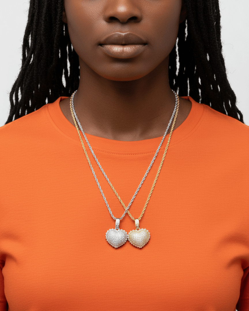 Person wearing two heart-shaped pendants on a plain background