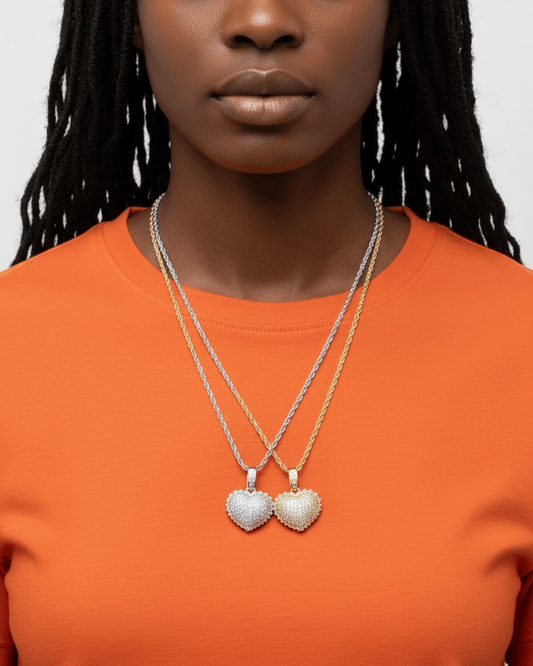 Person wearing two heart-shaped pendants on a plain background