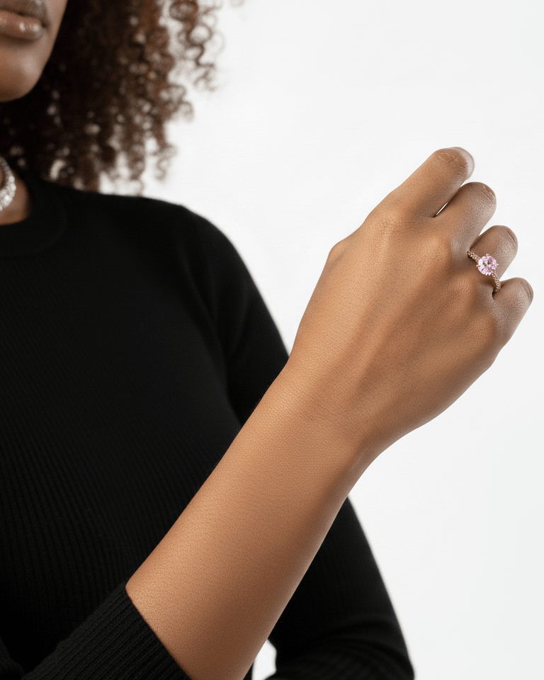 Person wearing a black top with a white background showing a pink diamond ring