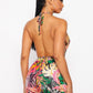 Woman wearing a colorful floral halter top shorts romper on a white background, back view