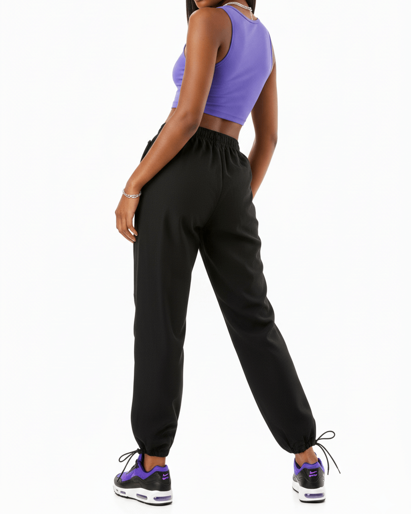 Woman wearing a purple crop top and black pants on a white background