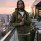 Man in a green tracksuit standing on a rooftop with cityscape in the background