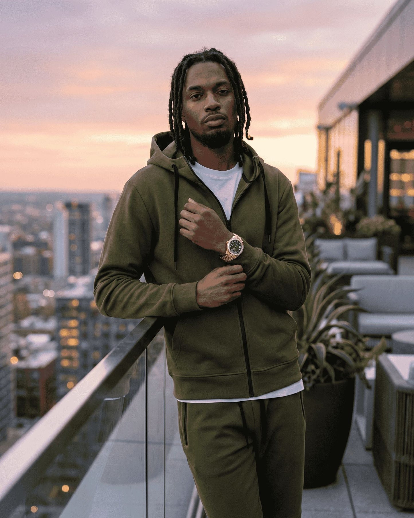 Man in a green tracksuit standing on a rooftop with cityscape in the background